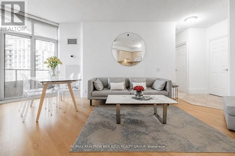 A modern living room with a grey rug, a white sofa, a wooden coffee table and a round mirror on the wall.