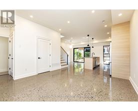 A spacious, well-lit living room with a marble floor and a staircase leading to the upper level.