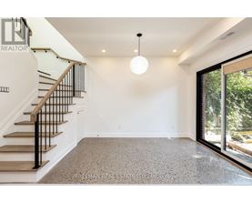 A spacious room with a staircase and a hanging light fixture.
