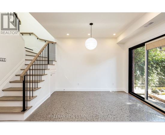 A spacious room with a staircase and a hanging light fixture.