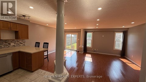 A real estate photo of a kitchen and living room with a dining table and chairs.