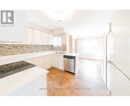 A kitchen with white cabinets and a stone backsplash.