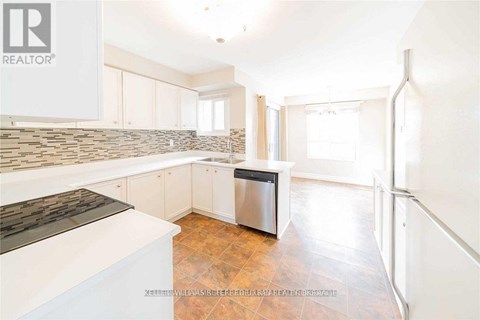 A kitchen with white cabinets and a stone backsplash.
