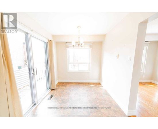 A spacious room with a tiled floor and a chandelier hanging from the ceiling.