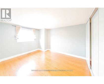 A room with wooden flooring and a window with curtains.