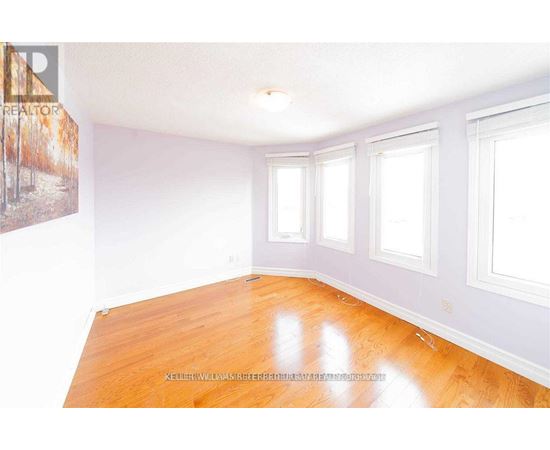 A room with wooden floors and white walls with three windows.