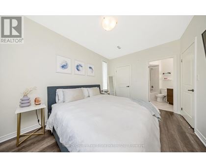 A bedroom with a large bed and a nightstand with a lamp.