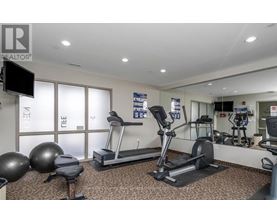 A gym with a treadmill, exercise balls, and a television.