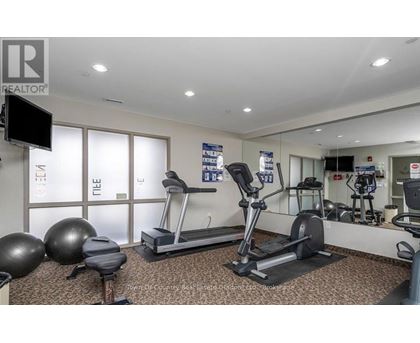A gym with a treadmill, exercise balls, and a television.