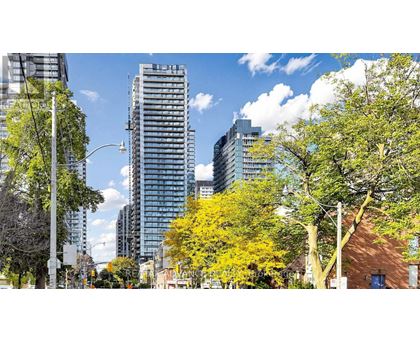 A cityscape with trees and buildings under a blue sky.