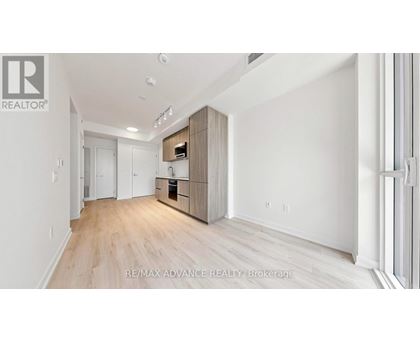 A spacious room with wooden flooring and white walls, featuring a built-in cabinet system.