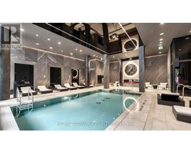 A large indoor swimming pool with lounge chairs and a tiled floor.