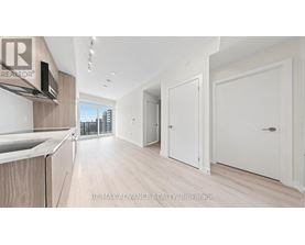 A modern kitchen with white cabinets and a wooden floor.