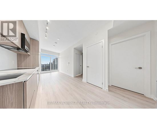 A modern kitchen with white cabinets and a wooden floor.