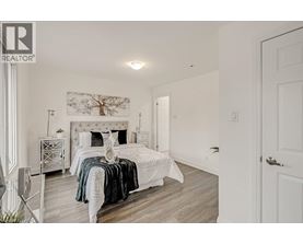 A bedroom with a white bed and a white dresser.
