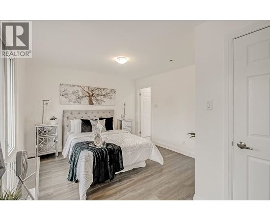 A bedroom with a white bed and a white dresser.