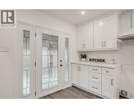 A kitchen with white cabinets and a glass door.