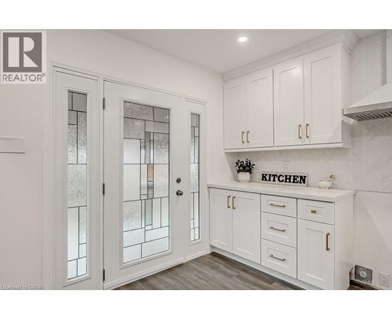 A kitchen with white cabinets and a glass door.