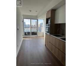 A kitchen with wooden floors and a large window overlooking a cityscape.