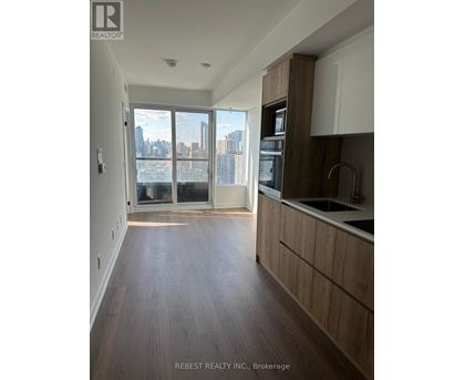 A kitchen with wooden floors and a large window overlooking a cityscape.