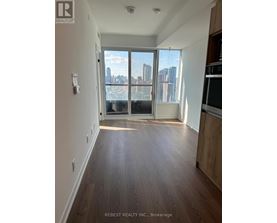 A spacious room with wooden flooring and a view of the city through large windows.