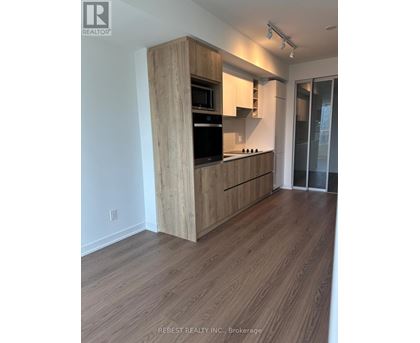 A kitchen with wooden cabinets and a black fridge.