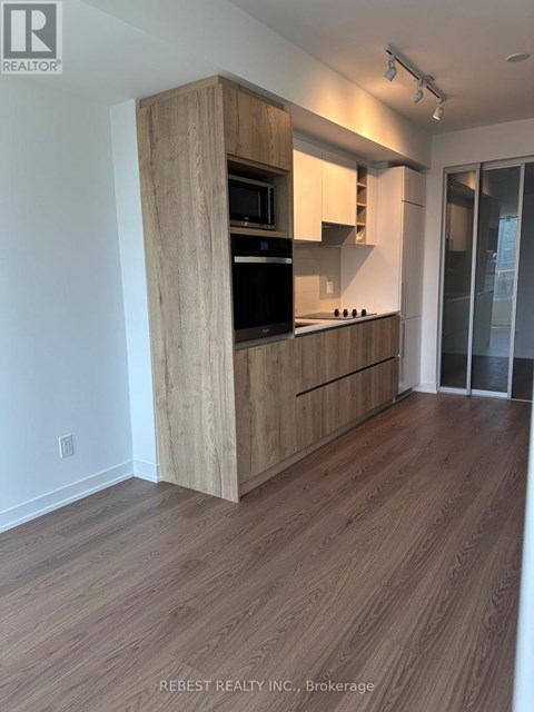 A kitchen with wooden cabinets and a black fridge.