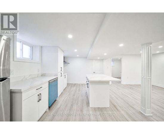 A white kitchen with a refrigerator, cabinets, and a countertop.