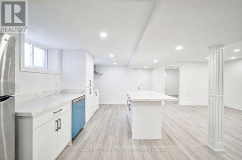 A white kitchen with a refrigerator, cabinets, and a countertop.