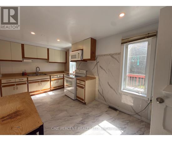A kitchen with white cabinets and a marble floor.