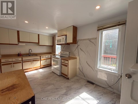 A kitchen with white cabinets and a marble floor.