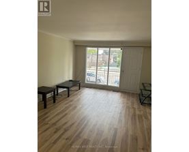 A room with wooden flooring and a sliding glass door leading to a balcony.