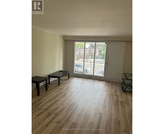 A room with wooden flooring and a sliding glass door leading to a balcony.