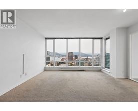 A large, empty room with a view of the cityscape outside the window.