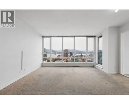 A large, empty room with a view of the cityscape outside the window.