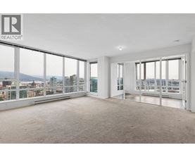 A large, empty room with a view of the cityscape outside the windows.
