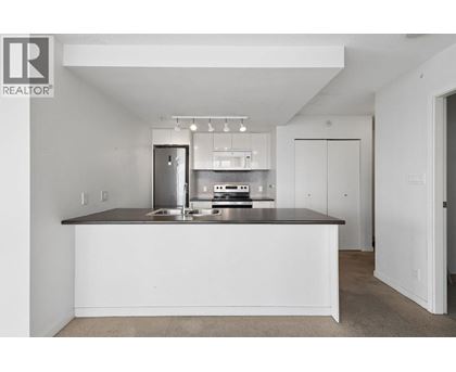A white kitchen with a countertop and a fridge.