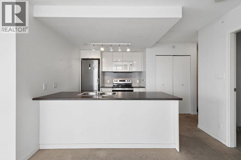 A white kitchen with a countertop and a fridge.