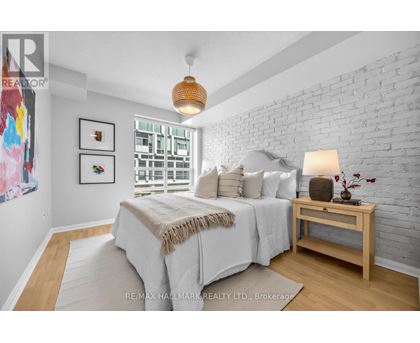 A bedroom with a white brick wall and a bed with a white comforter.