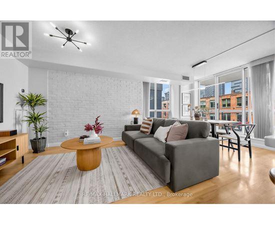 A living room with a grey couch, a wooden coffee table, and a large window with a view of the city.