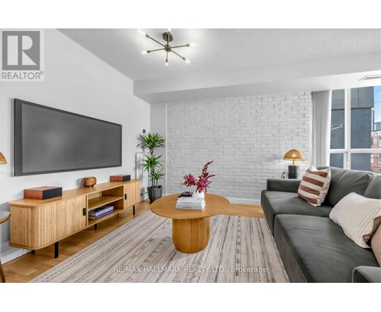 A living room with a grey couch, a wooden coffee table, and a flat screen TV mounted on the wall.