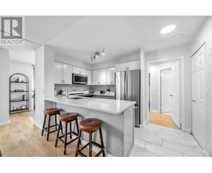 A modern kitchen with white cabinets and a bar area.
