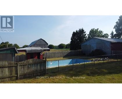 A pool in a backyard with a fence and a barn in the background.