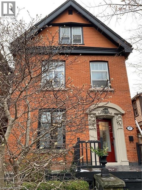 A red brick house with a black roof and a white door.
