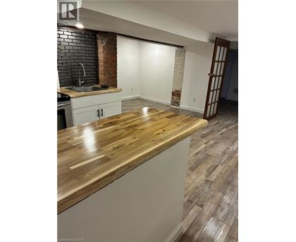 A kitchen with a wooden counter top and a brick wall.