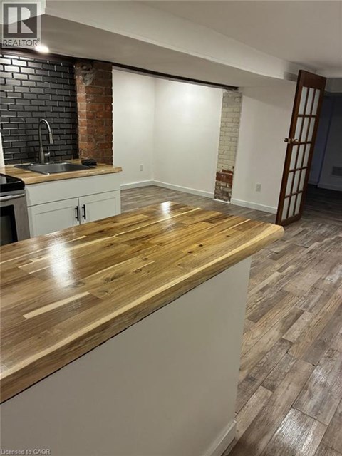 A kitchen with a wooden counter top and a brick wall.