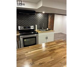 A kitchen with a black brick wall and a wooden floor.