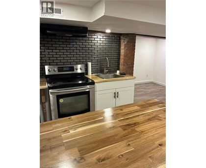 A kitchen with a black brick wall and a wooden floor.