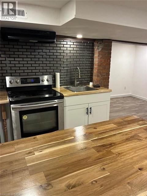 A kitchen with a black brick wall and a wooden floor.