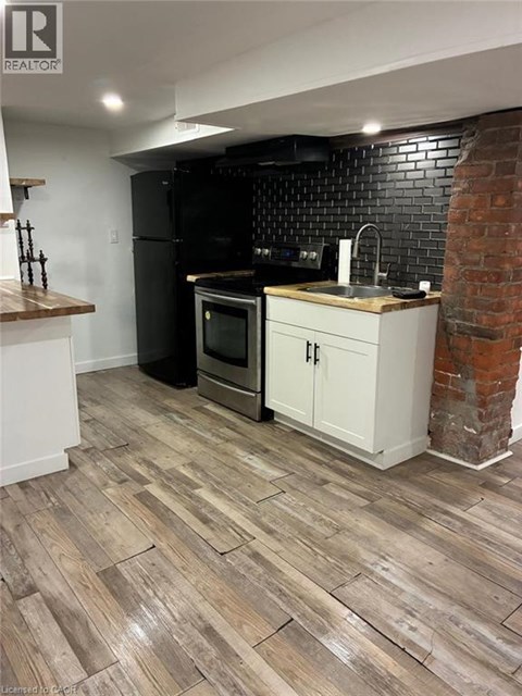 A kitchen with a black fridge and white cabinets.